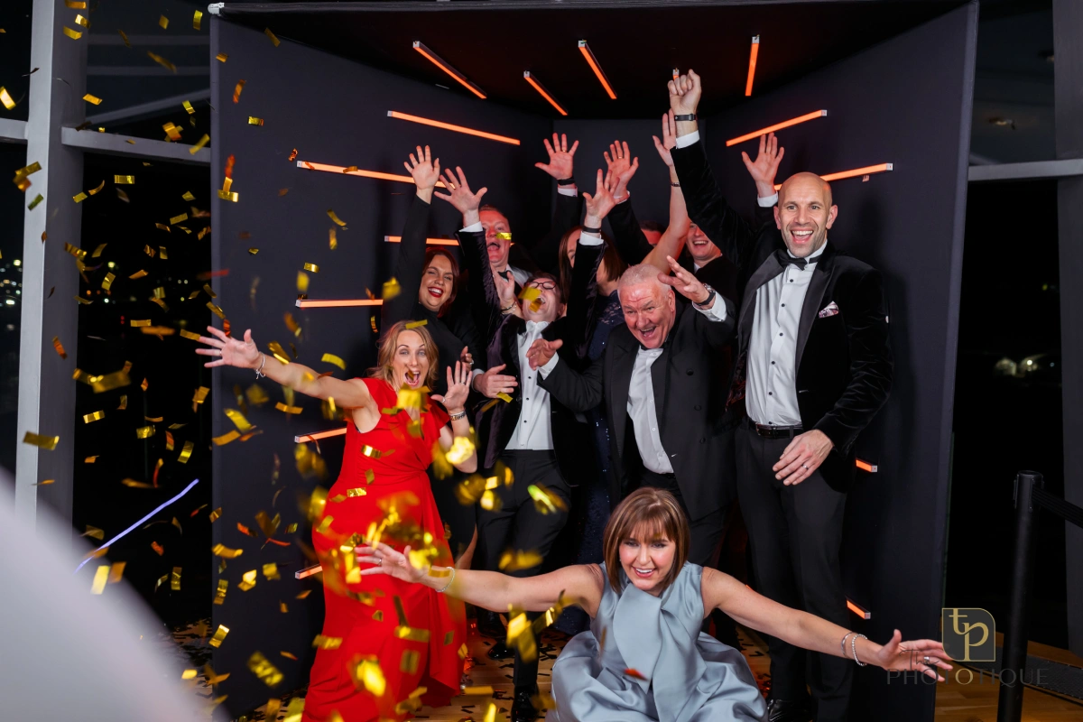 LED-lit Vogue-style photo booth enclosure with guests posing in high-fashion outfits.